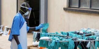 Ugandan worker collects a rubber glove from an airing line during a visit by the Director-General of the World Health Organisation at Mulago National Referral Hospital Isolation Unit.
