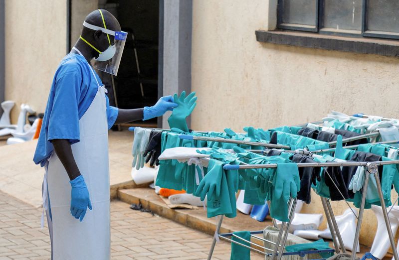 Ugandan worker collects a rubber glove from an airing line during a visit by the Director-General of the World Health Organisation at Mulago National Referral Hospital Isolation Unit.