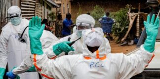 Civil Protection team members in personal protective equipment disinfect an area after handling the body of a man who died of Ebola in Bunia, Democratic Republic of Congo.