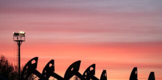 Oil rises as Donald Trump threatens sanctions on Iran partners Pump jacks operate at the Airankol oil field under a sky with glowing sunset clouds.