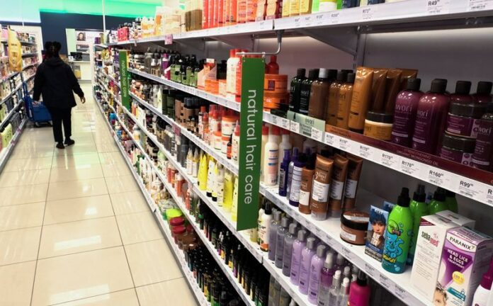 Worker walking past an aisle of hair products at a Clicks store in Johannesburg