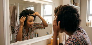 A Black South African woman with healthy afro-textured hair examining her scalp.