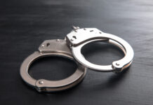 Pensioner joins former colleagues behind bars in Mpumalanga looting case Handcuffs on dark wooden background