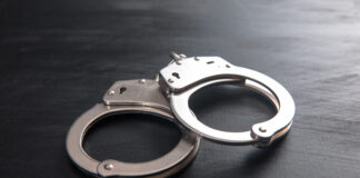Pensioner joins former colleagues behind bars in Mpumalanga looting case Handcuffs on dark wooden background